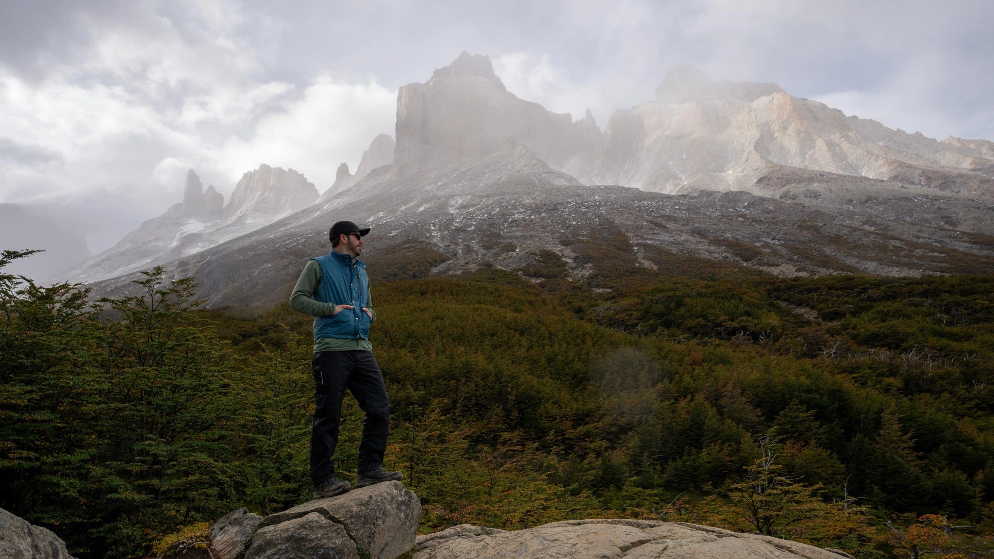 Man in Monarch Flyway vest hiking with mountain view